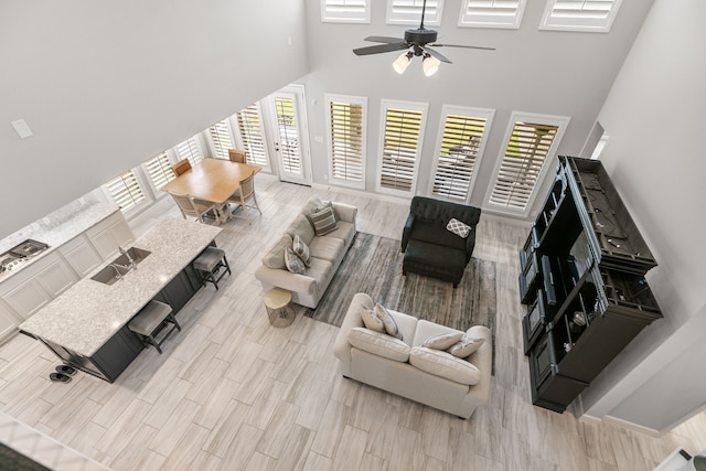 living room with wood finish floors, a towering ceiling, and ceiling fan