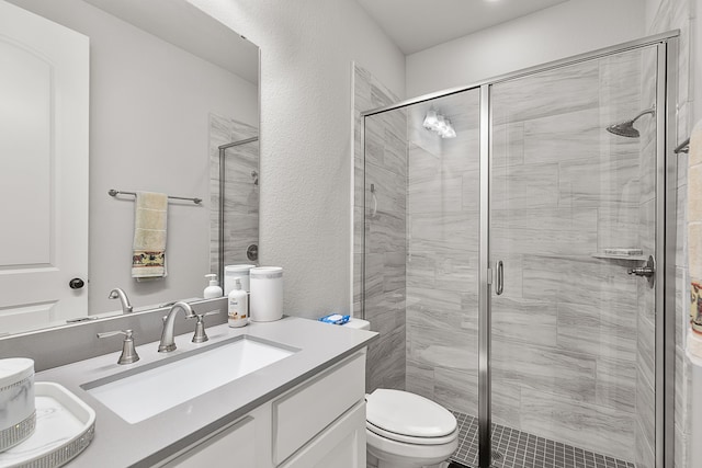 bathroom featuring a shower stall, toilet, vanity, and a textured wall