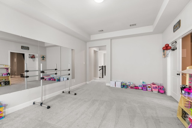 recreation room with a tray ceiling, carpet, visible vents, and baseboards