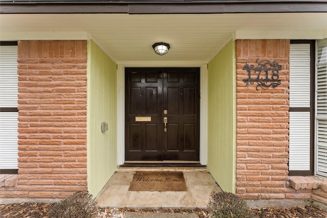 view of exterior entry featuring brick siding