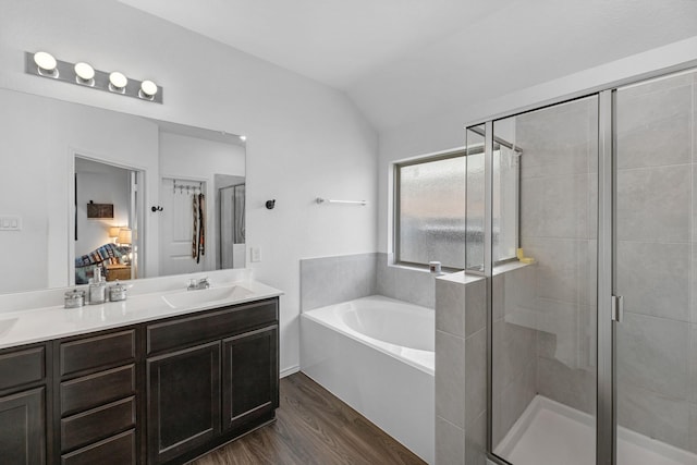 ensuite bathroom with a sink, a garden tub, a stall shower, and wood finished floors