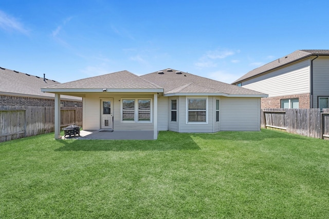 back of property featuring a lawn, a fenced backyard, an outdoor fire pit, roof with shingles, and a patio area