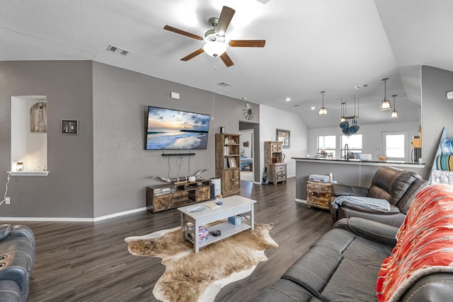 living area with visible vents, ceiling fan, baseboards, lofted ceiling, and dark wood-style floors