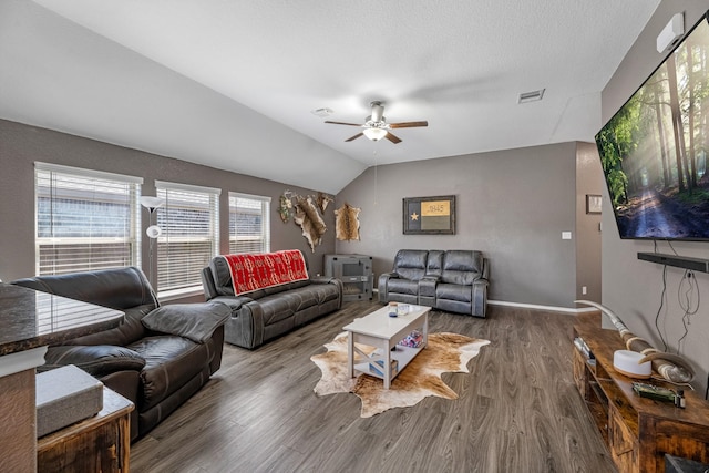 living area with visible vents, wood finished floors, baseboards, lofted ceiling, and ceiling fan