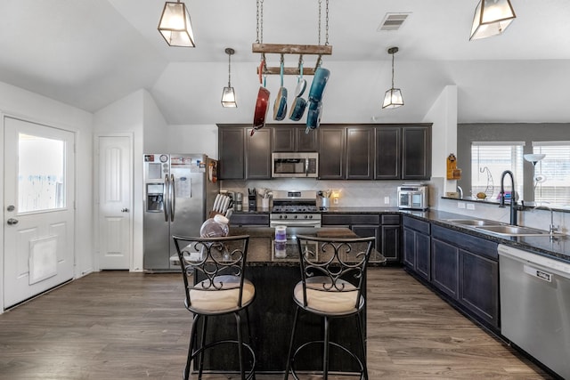 kitchen with a sink, visible vents, appliances with stainless steel finishes, and vaulted ceiling