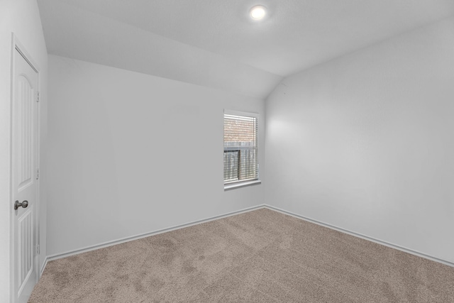 carpeted empty room with vaulted ceiling and baseboards