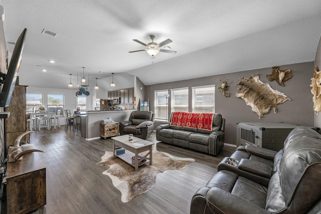 living room with visible vents, ceiling fan, vaulted ceiling, a textured ceiling, and dark wood-style flooring