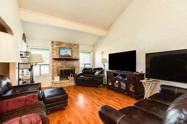 living area featuring lofted ceiling with beams, wood finished floors, a fireplace, and a wealth of natural light