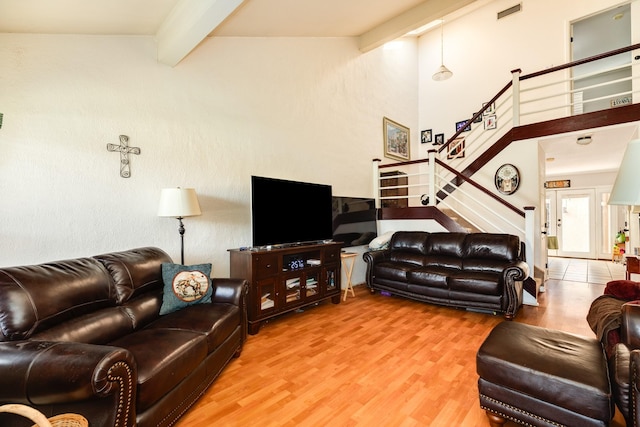 living area featuring stairway, wood finished floors, visible vents, high vaulted ceiling, and beamed ceiling