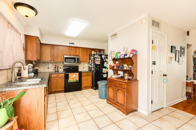 kitchen with visible vents, decorative backsplash, brown cabinets, black appliances, and a sink