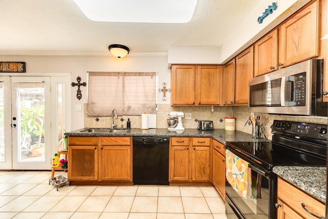 kitchen featuring tasteful backsplash, brown cabinets, light tile patterned flooring, black appliances, and a sink