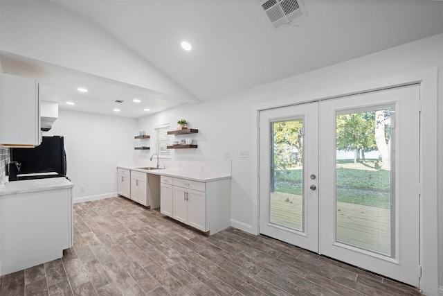 kitchen featuring wood finished floors, visible vents, open shelves, a sink, and black refrigerator