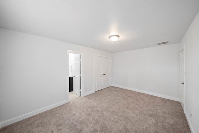 unfurnished bedroom featuring visible vents, baseboards, light colored carpet, and a closet