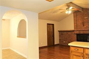 kitchen with baseboards, lofted ceiling with beams, a ceiling fan, and wood finished floors