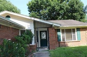 entrance to property with brick siding and a yard