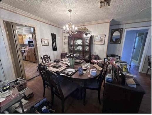 dining space featuring visible vents, a notable chandelier, ornamental molding, and a textured ceiling