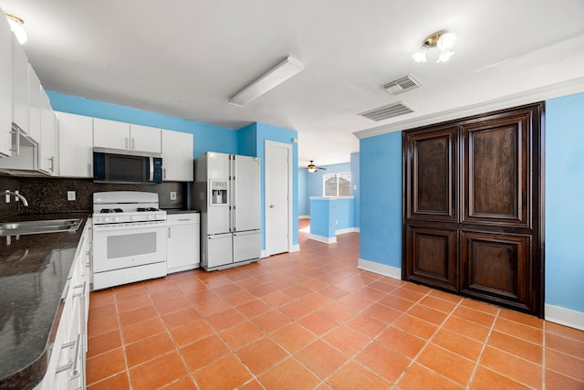 kitchen featuring visible vents, a sink, tasteful backsplash, white appliances, and white cabinets