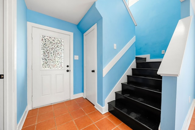 tiled foyer featuring stairway and baseboards