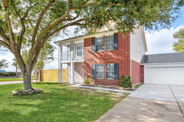 view of front of home with brick siding, fence, a front yard, a balcony, and driveway