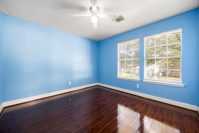 empty room featuring ceiling fan, visible vents, baseboards, and wood-type flooring