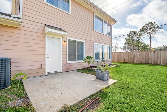 entrance to property with central AC unit, a lawn, a patio, and fence