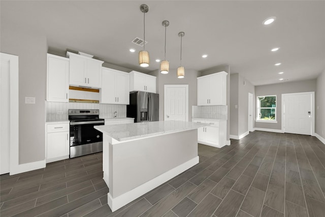 kitchen with visible vents, a kitchen island, tasteful backsplash, white cabinetry, and appliances with stainless steel finishes