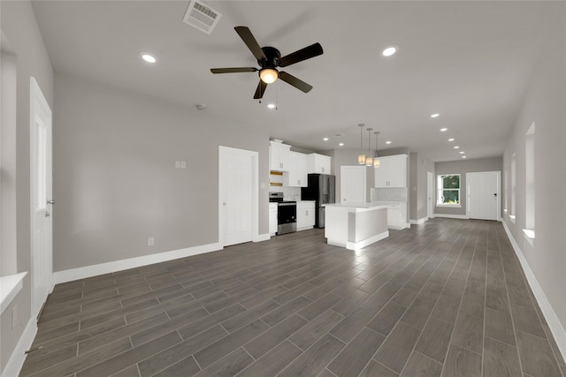 unfurnished living room with dark wood-style floors, visible vents, and recessed lighting