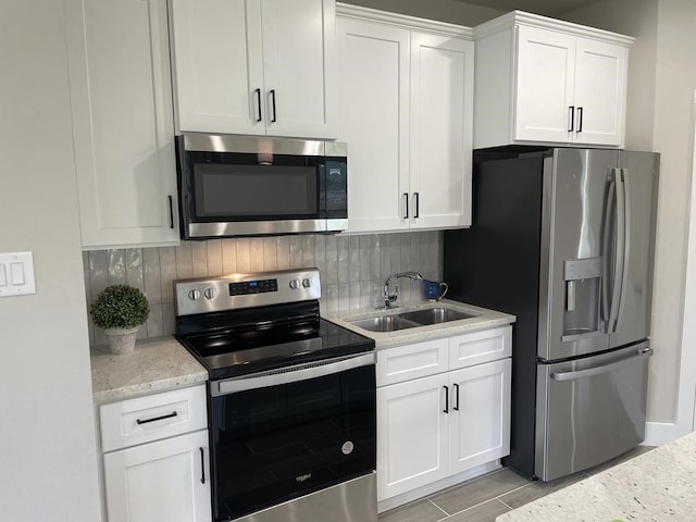 kitchen with wood finish floors, decorative backsplash, stainless steel appliances, white cabinetry, and a sink