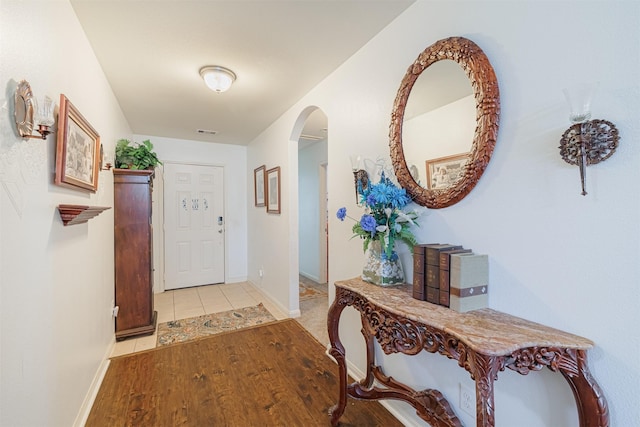 interior space featuring visible vents, arched walkways, baseboards, and light wood finished floors