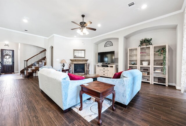 living area featuring visible vents, ceiling fan, arched walkways, a glass covered fireplace, and dark wood-style flooring