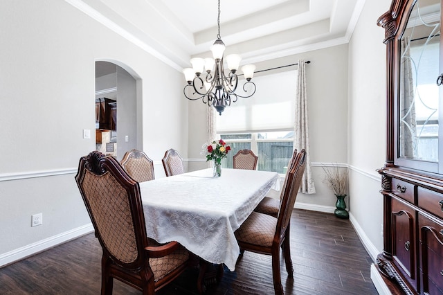 dining area featuring a tray ceiling, dark wood finished floors, arched walkways, baseboards, and a chandelier