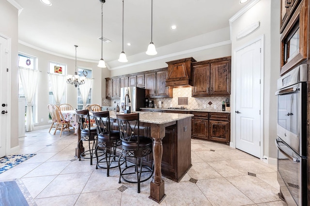 kitchen with premium range hood, a kitchen breakfast bar, tasteful backsplash, stainless steel appliances, and a chandelier