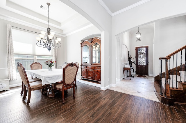 dining room featuring dark wood-type flooring, a notable chandelier, stairway, arched walkways, and a raised ceiling