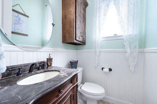 bathroom featuring wainscoting, toilet, and vanity