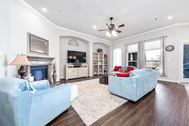 living room featuring baseboards, wood finished floors, a glass covered fireplace, and crown molding