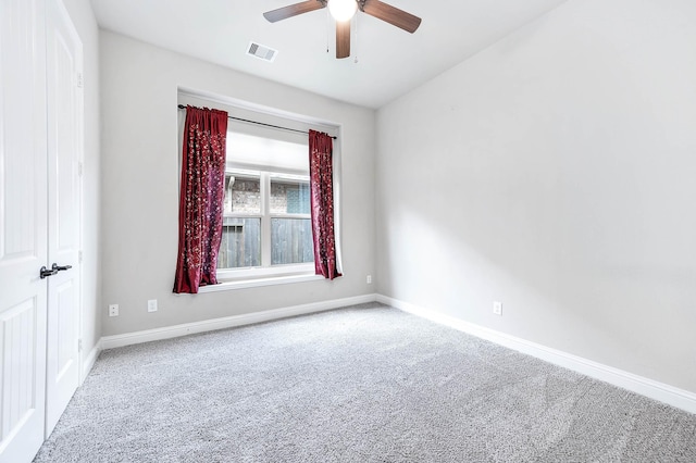 carpeted empty room featuring visible vents, baseboards, and a ceiling fan