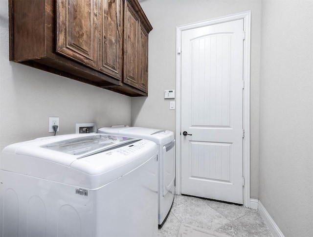 washroom featuring baseboards, cabinet space, and washing machine and dryer