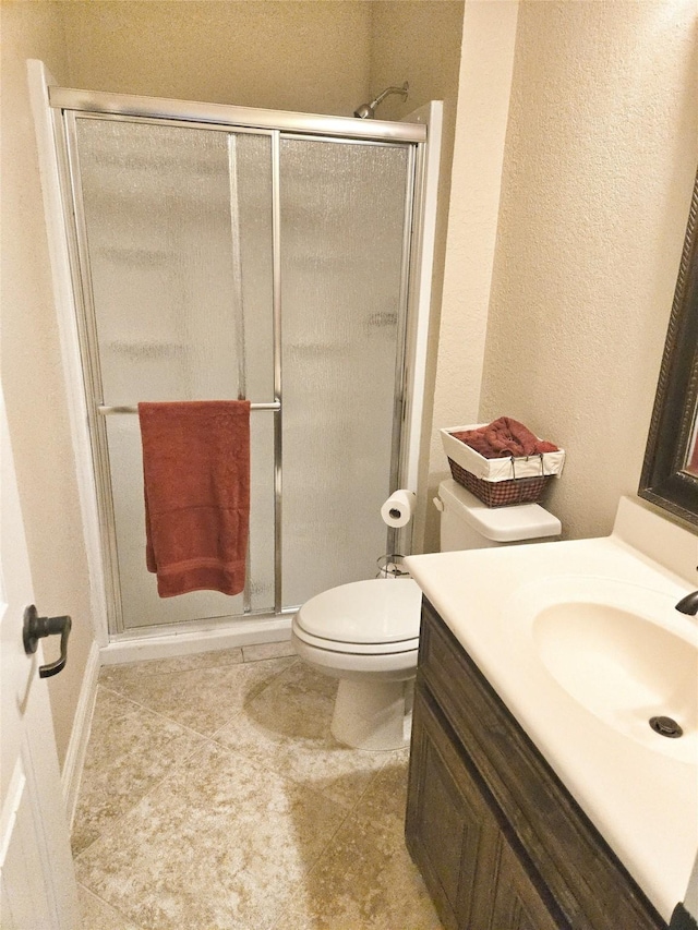 full bath with a shower stall, vanity, toilet, and a textured wall