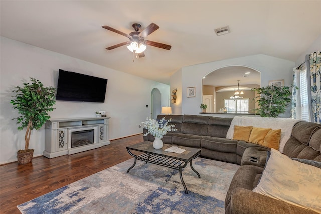 living room with visible vents, ceiling fan with notable chandelier, wood finished floors, arched walkways, and lofted ceiling