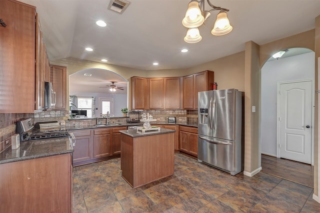 kitchen featuring visible vents, arched walkways, a center island, a sink, and stainless steel appliances