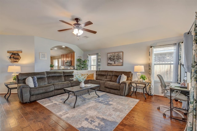 living room with arched walkways, a ceiling fan, baseboards, lofted ceiling, and hardwood / wood-style flooring