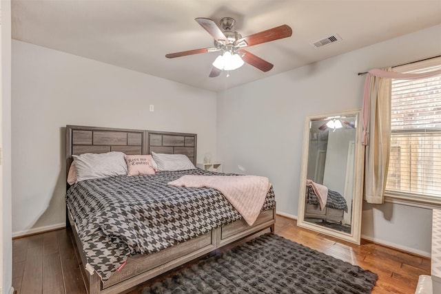 bedroom featuring visible vents, baseboards, ceiling fan, and wood finished floors
