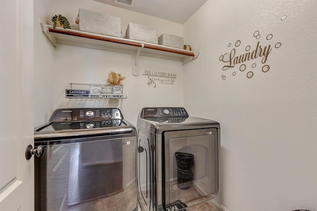 clothes washing area with laundry area, visible vents, and washer and clothes dryer