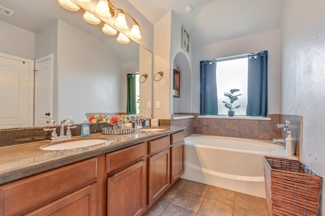 full bathroom featuring a sink, tile patterned floors, a garden tub, and double vanity