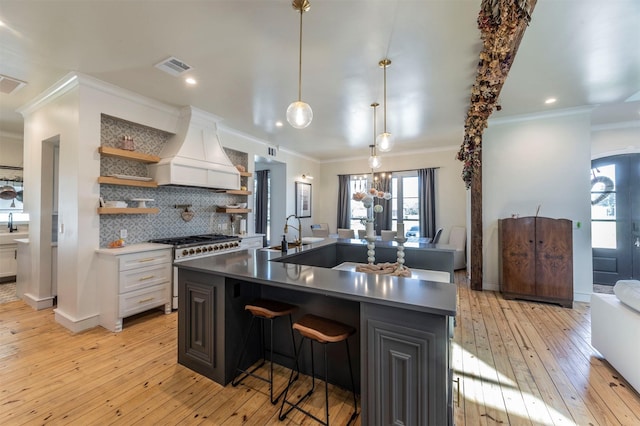 kitchen featuring visible vents, open shelves, tasteful backsplash, stainless steel stove, and custom exhaust hood