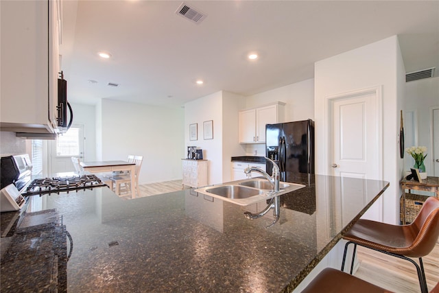 kitchen featuring visible vents, black fridge, range, and a sink