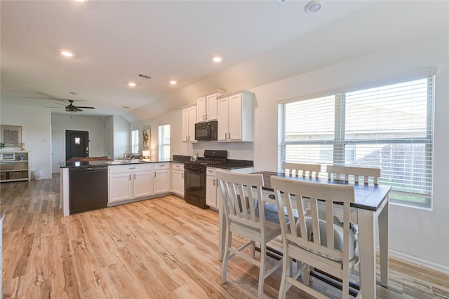 kitchen featuring visible vents, a peninsula, black appliances, white cabinetry, and dark countertops