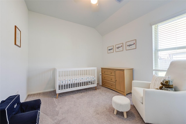 carpeted bedroom featuring a crib, vaulted ceiling, a ceiling fan, and visible vents