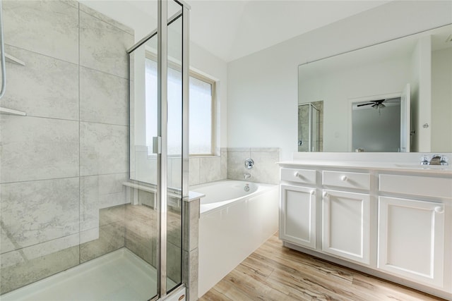 bathroom featuring double vanity, a stall shower, wood finished floors, a bath, and a sink