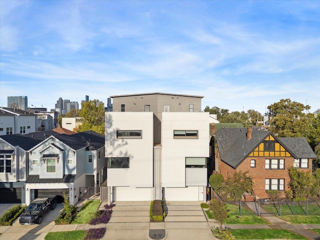 view of front of house with stucco siding, fence, a residential view, concrete driveway, and a garage